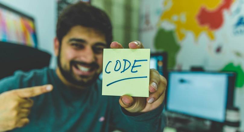 Smiling man with sticky note showing code illustration - Photo by Hitesh Choudhary on Unsplash