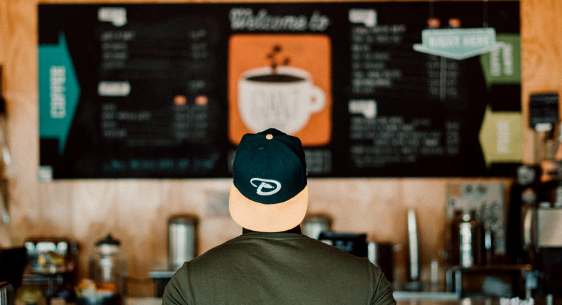 Photo of person wearing a cap staring at a menu board shot by Levi Elizaga on Unsplash